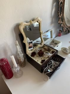 an open jewelry box sitting on top of a table next to a mirror and candle