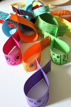 several colorful paper bracelets with faces on them sitting on top of a white table