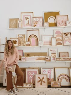 a woman is sitting on a chair in front of some art pieces and smiling at the camera