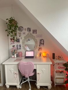 a white desk topped with a laptop computer under a stair case next to a potted plant