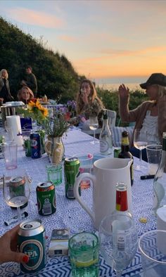 a group of people sitting around a table with drinks and water glasses on top of it