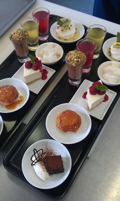 several desserts are arranged on two black trays