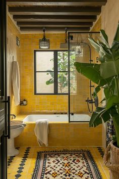 a bathroom with yellow tiles and a white bathtub next to a plant in a basket