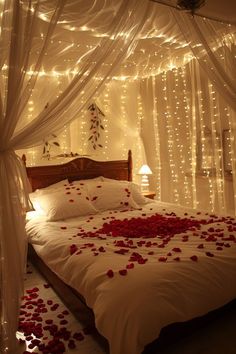 a bed with rose petals on it and lights in the room behind it that is lit up