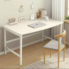 a white desk with a laptop on top of it next to a chair in front of a window