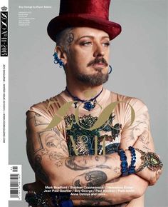 a man with tattoos and a red hat on top of his head is posing for a magazine cover