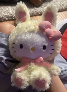 a hello kitty stuffed animal laying on top of someone's lap with her hand