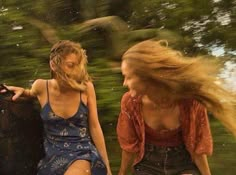 two young women sitting on the back of a boat in the water, one with her hair blowing in the wind