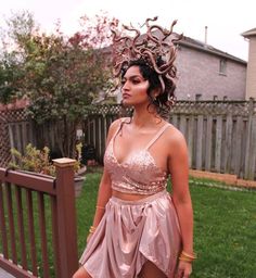 a woman in a pink dress standing next to a fence with her hair blowing back