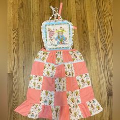 a pink and white dress hanging on a wooden wall next to a brown floor with wood floors