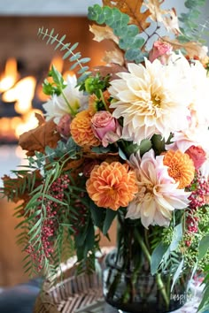 a vase filled with lots of flowers on top of a table next to a fire place