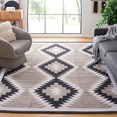 a living room area with two couches and a rug on the floor in front of a large window