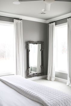 a bed room with a large window and a mirror on the wall next to it