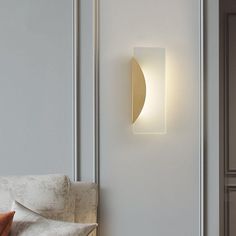 a white wall light mounted on the side of a wall next to a couch and pillows