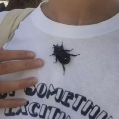 a person wearing a white shirt with a black bug on it