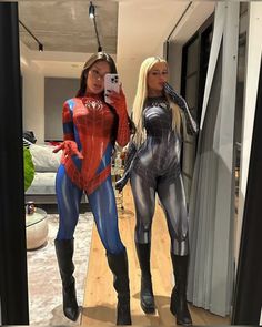 two women dressed as spider - man and black widow standing in front of a mirror