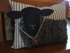 a black sheep pillow sitting on top of a wooden bench next to a clock and window