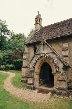 an old stone church with a steeple and flowers on the front door is shown