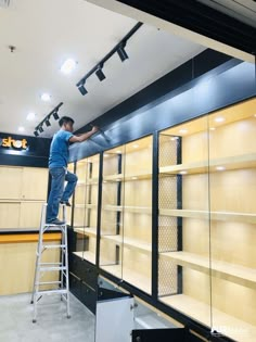 a man standing on a ladder working on shelves