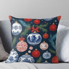 a blue and white christmas ornament throw pillow on a couch with red ornaments