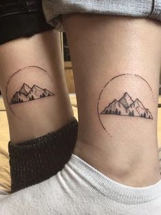 two people with matching tattoos on their legs, one has mountains and the other has a circle