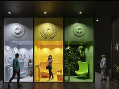 three people are walking in front of some colorful walls and chairs with plants on them