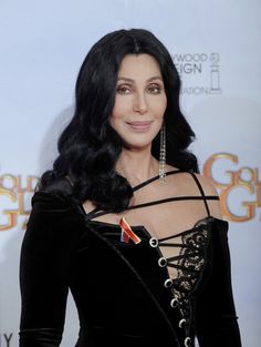 a woman with long black hair wearing a dress and holding an award in her hand