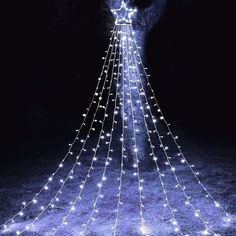 a lighted christmas tree in the dark with white lights on it's head and arms