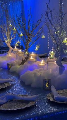 a table set up with candles, plates and trees in the middle of it covered in snow