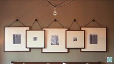 a chandelier hanging from the ceiling over a bed with four framed pictures on it