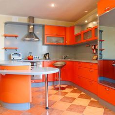 an orange kitchen with stainless steel appliances and stools