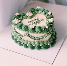 a green and white heart shaped cake sitting on top of a table