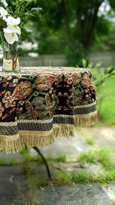 a vase filled with flowers sitting on top of a table covered in tassels