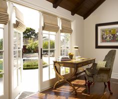 a chair and desk in a room with french doors leading to the outside patio area