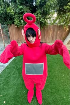 a person in a red lobster costume standing on grass with their arms out and eyes closed