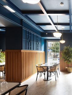 an empty restaurant with blue walls and wood paneling on the ceiling is pictured in this image