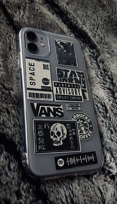 an iphone case with stickers on it laying on a fur covered surface in black and white