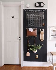 a chalkboard with some plants hanging on it and a clock above the door to the other room