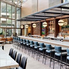 an empty bar with blue chairs and barstools in front of large glass windows