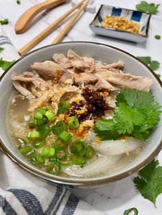 a bowl filled with meat and vegetables on top of a table next to chopsticks