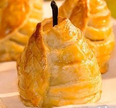 small pastries are lined up on a white plate with apples in the back ground