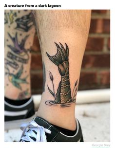 a man's foot with a tattoo on it and an alligator in the water