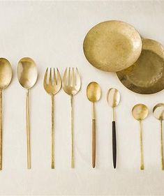 an assortment of gold colored utensils and spoons