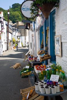 an outdoor market with lots of food and drinks on the side of the road in front of a white building