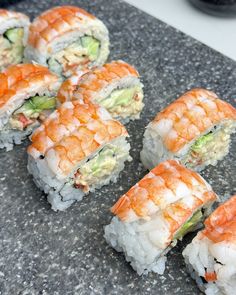 several sushi rolls are arranged on a granite counter top, ready to be eaten