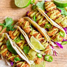 several tacos are lined up on a plate with limes and cilantro