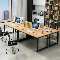 an office desk with two computers on it in front of a large window overlooking the city