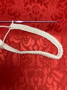 a piece of white string is tied to a red background with floral designs on it