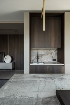 a modern kitchen with marble counter tops and wooden cabinetry, along with a couch