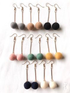 six pairs of earrings with different colored pom poms hanging from the ear hooks